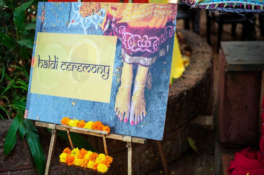 A hand-painted haldi ceremony sign banked with marigolds